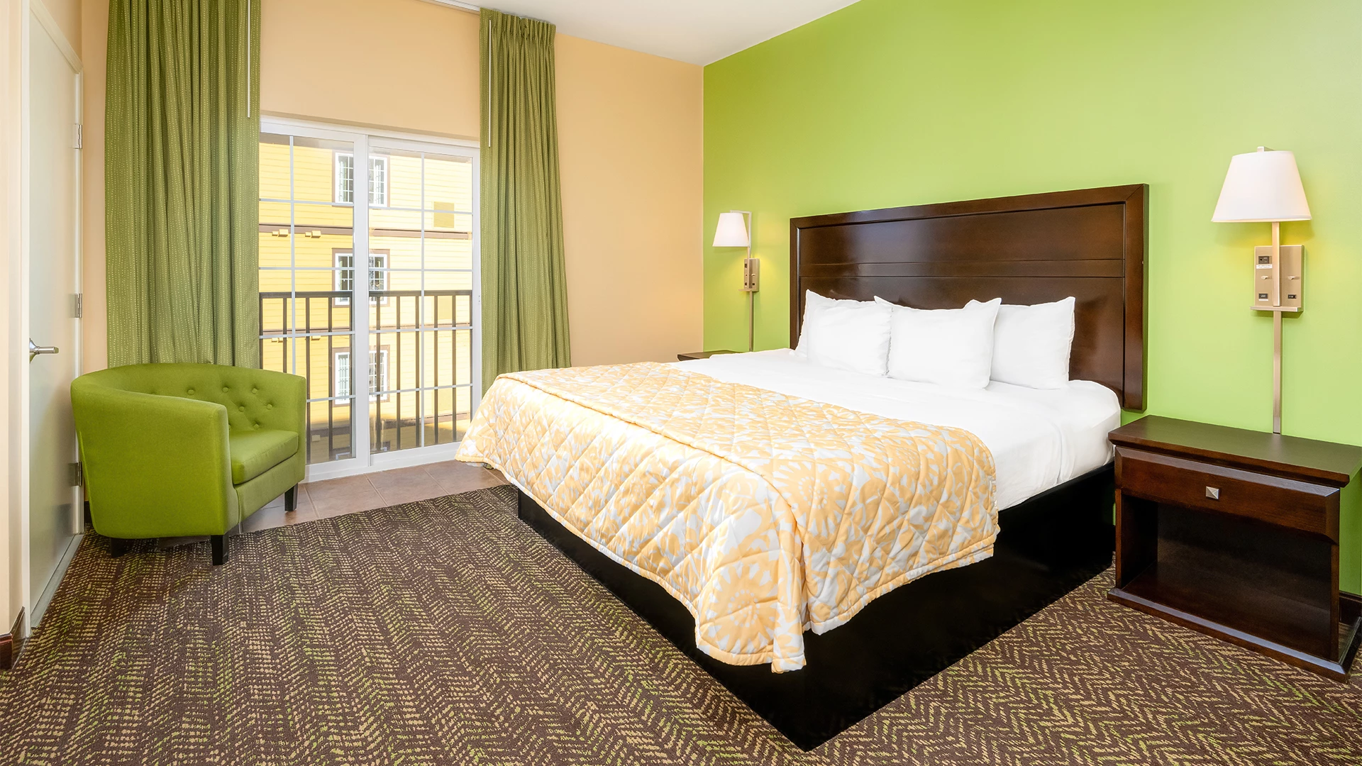 A hotel room with a bed, chair, nightstand, and balcony