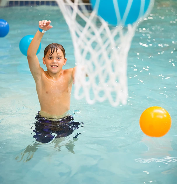 a boy playing in a pool with balls