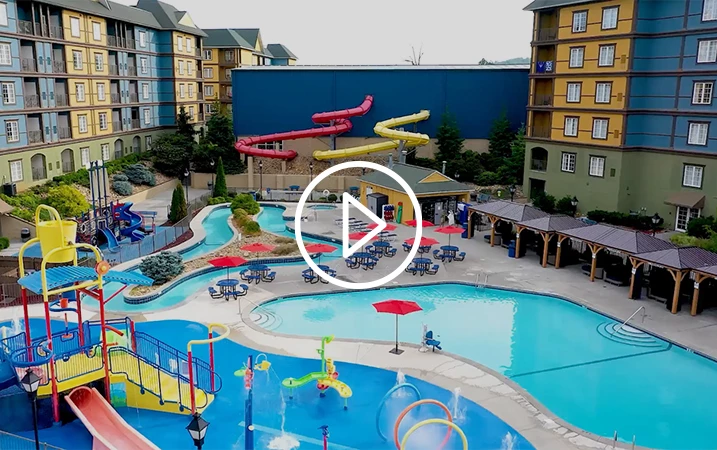 An overhead view of a hotel pool area with water slides and buildings.