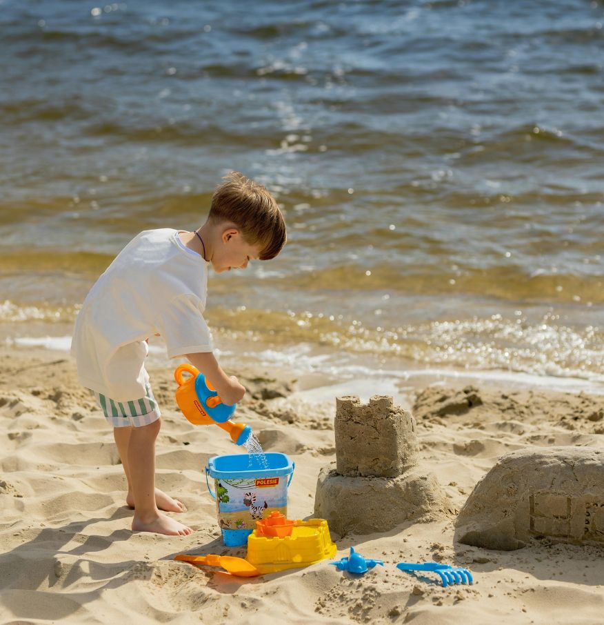 a boy playing with sand on a beach
