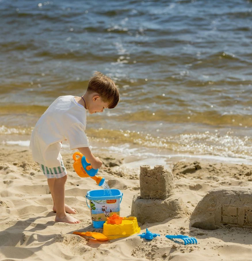 a boy playing with sand on a beach