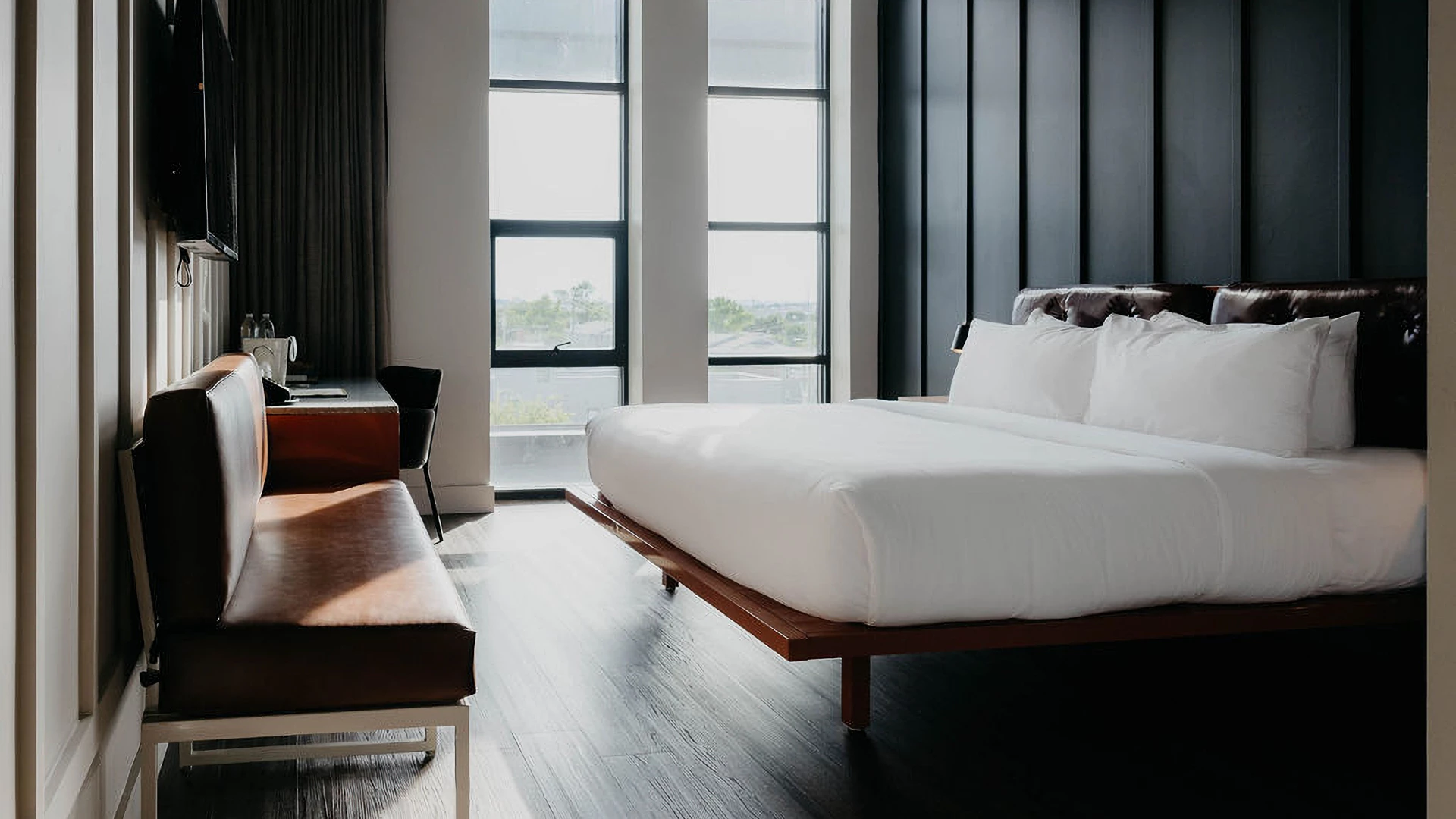 A hotel room with a large bed, desk, and window.
