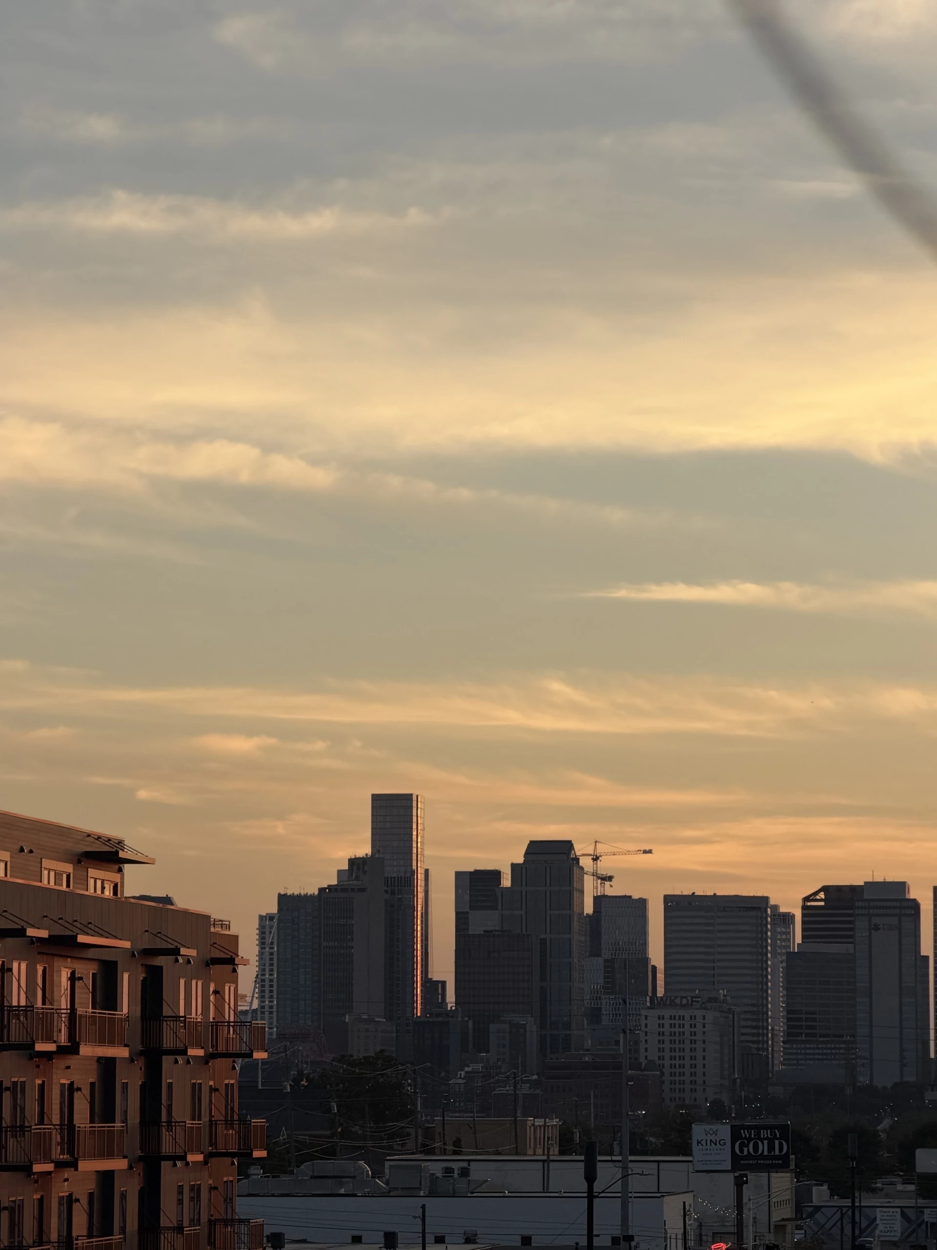 A city skyline at sunset with a cloudy sky