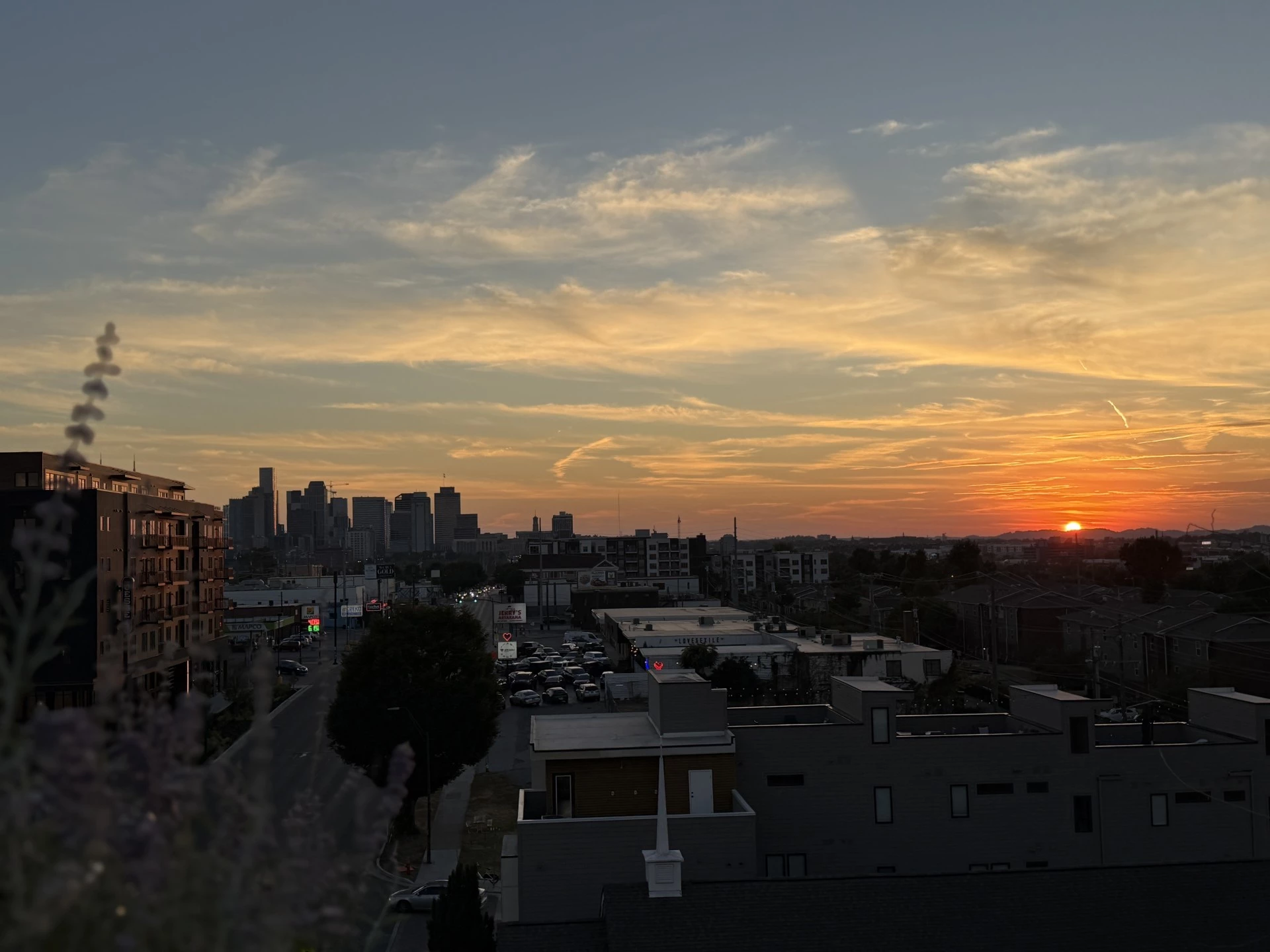A cityscape at sunset with a view of buildings and a road