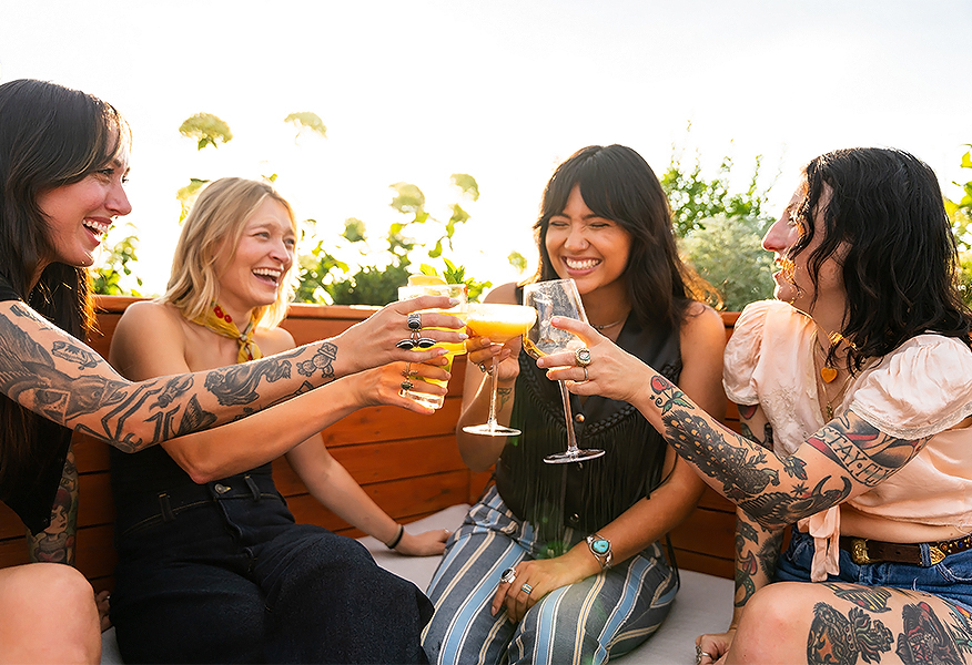 a group of people sitting on a bench and holding drinks