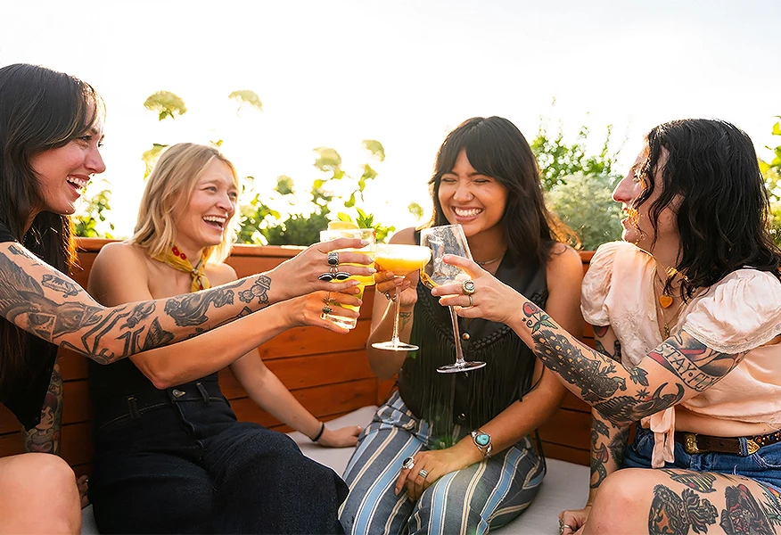 a group of people sitting on a bench and holding drinks