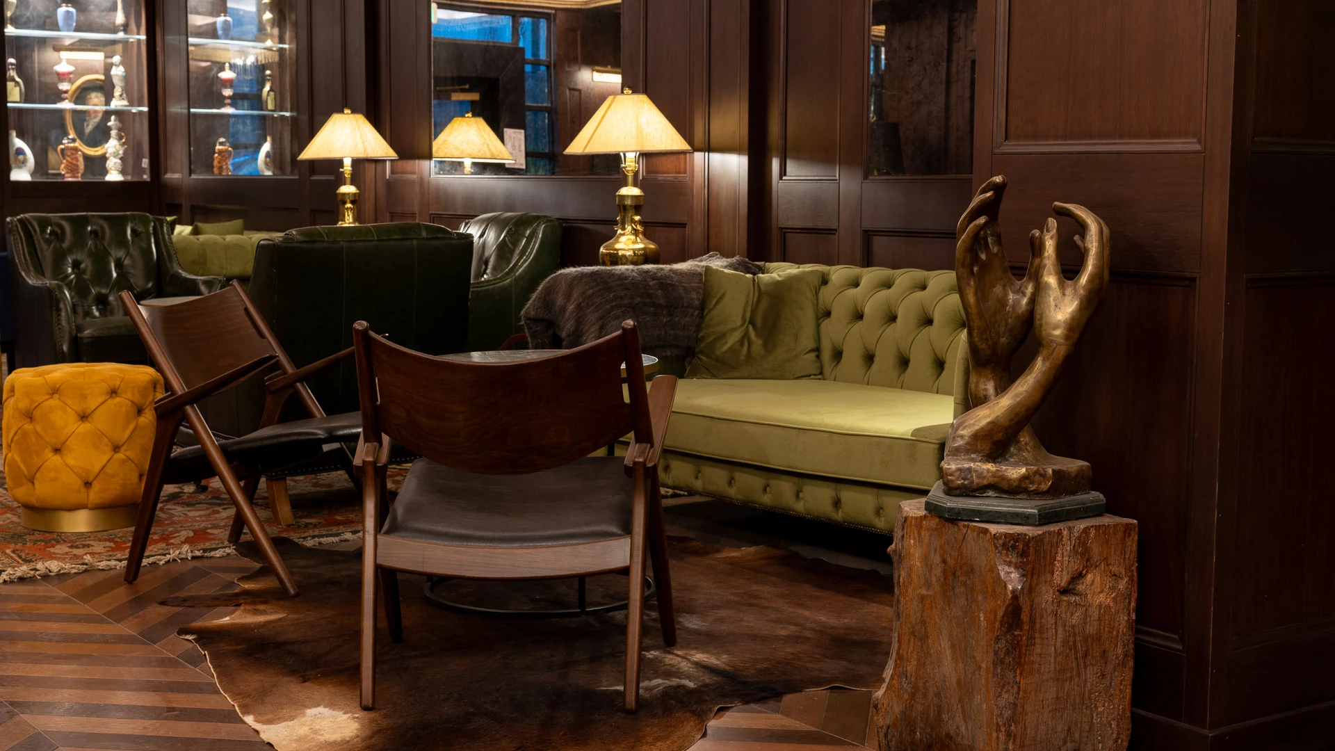 A cozy lobby area with a green sofa, armchairs, and a sculpture.