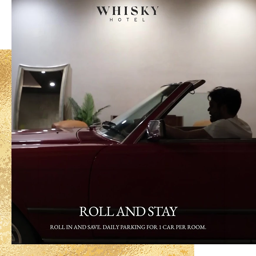 A man sitting in a red vintage convertible inside a hotel.
