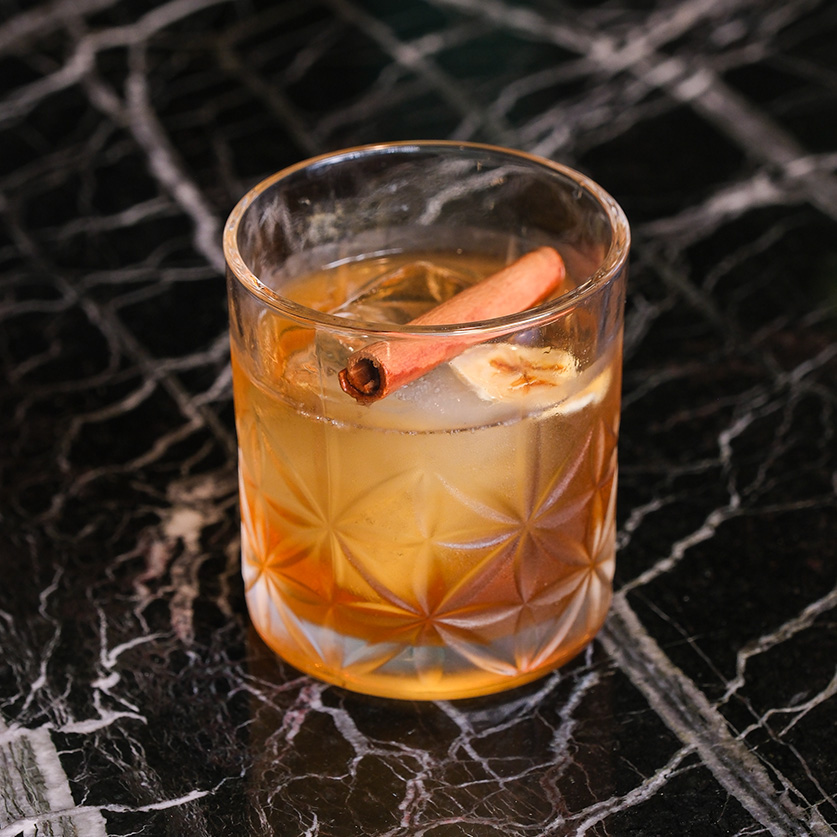 a glass of drink with a cinnamon stick and ice