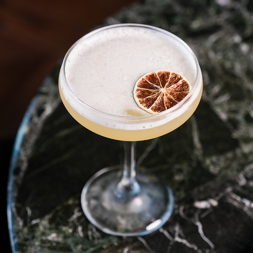 a glass with a drink and a slice of orange on top