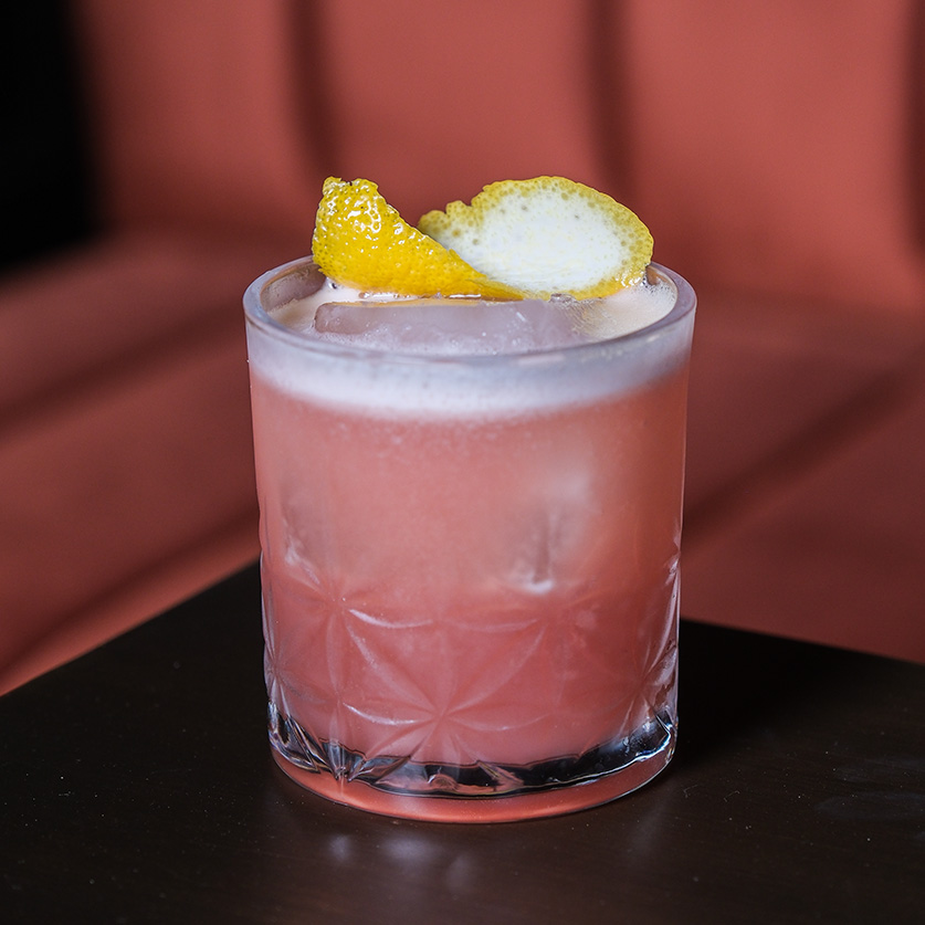 a pink drink with a lemon wedge on top of it