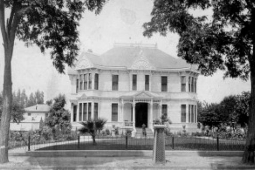 a large white house with a fence and trees