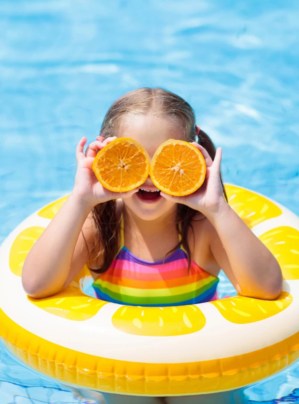 a girl in a pool holding oranges