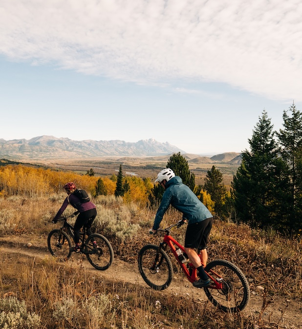 two people riding bikes on a trail