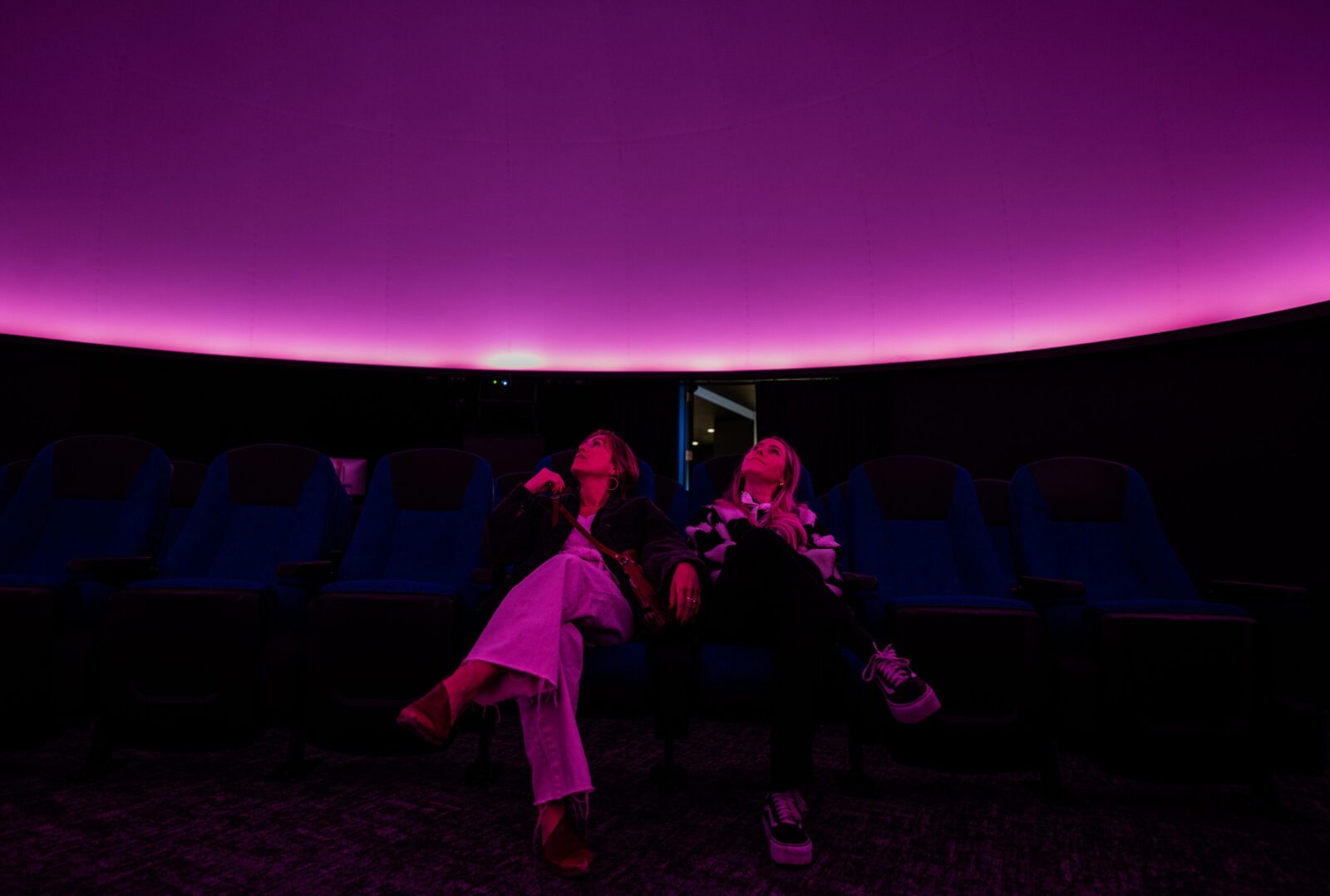 two women sitting on a chair in a theater