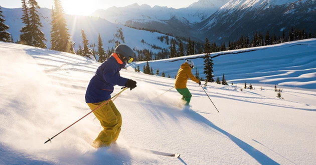 a couple of people skiing down a mountain