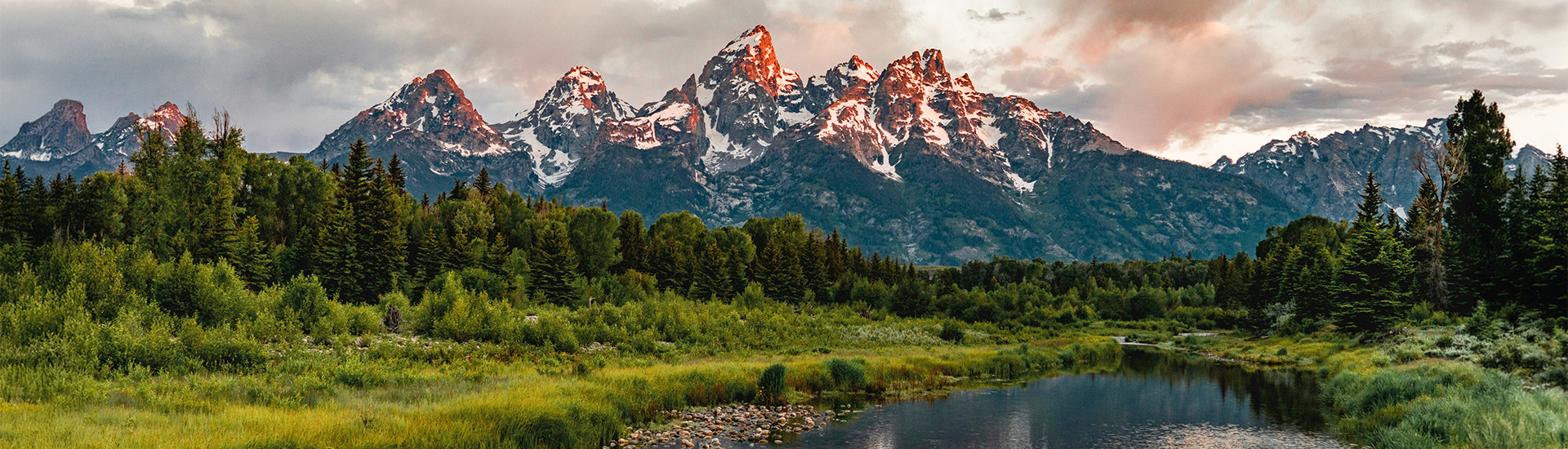 a snowy mountain range with trees and a lake