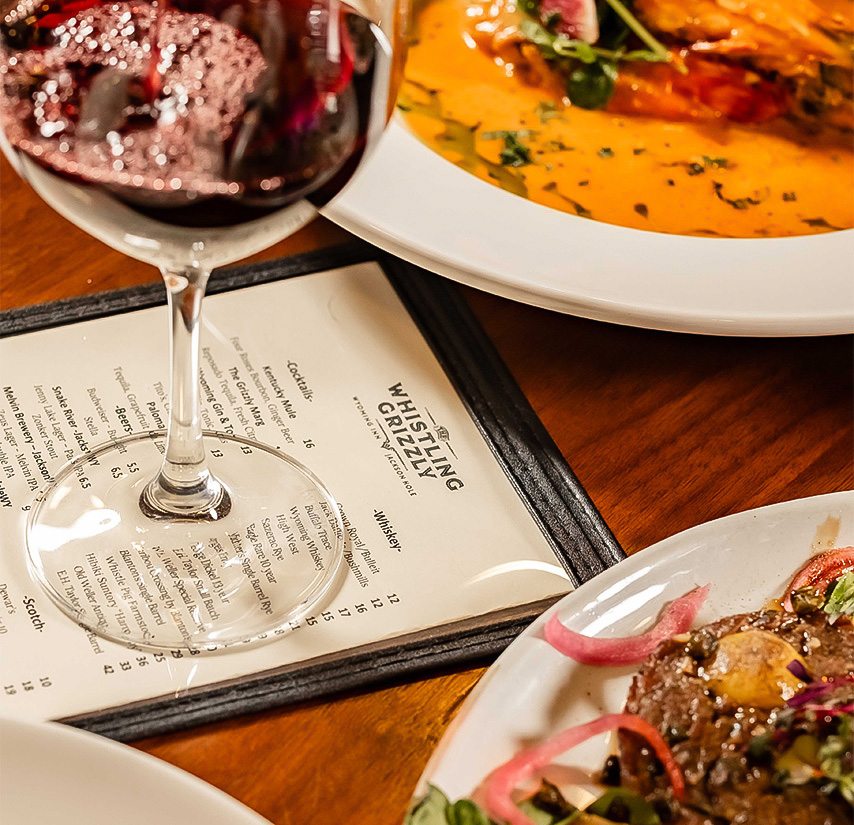 a glass of wine next to plates of food