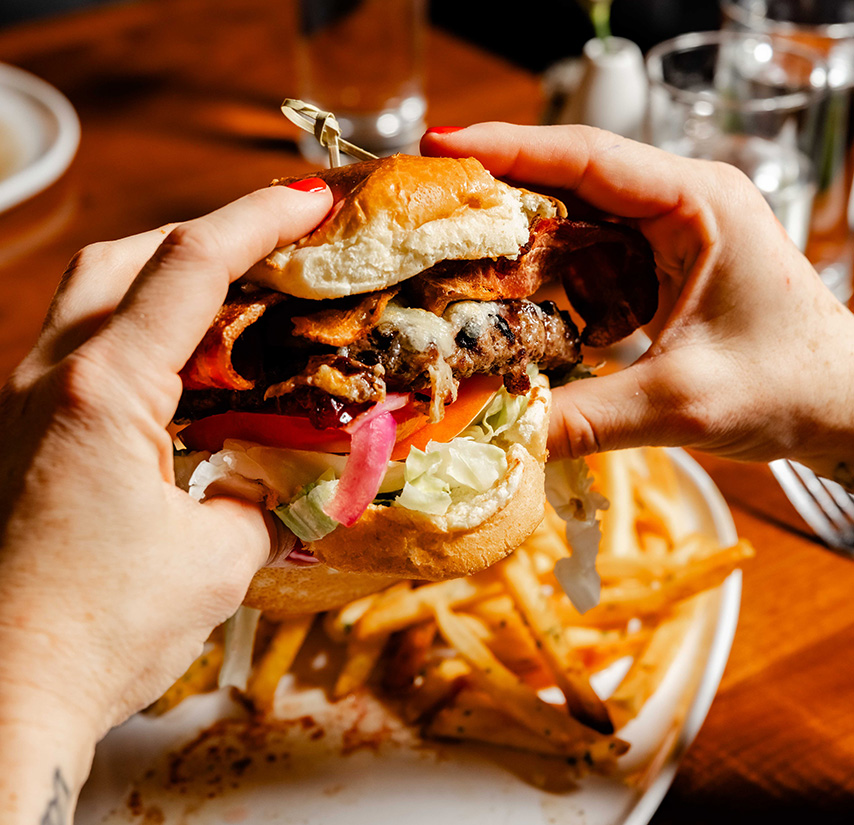 a person holding a burger with fries