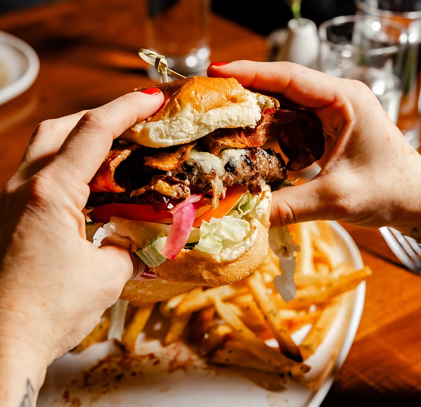 a person holding a burger with fries