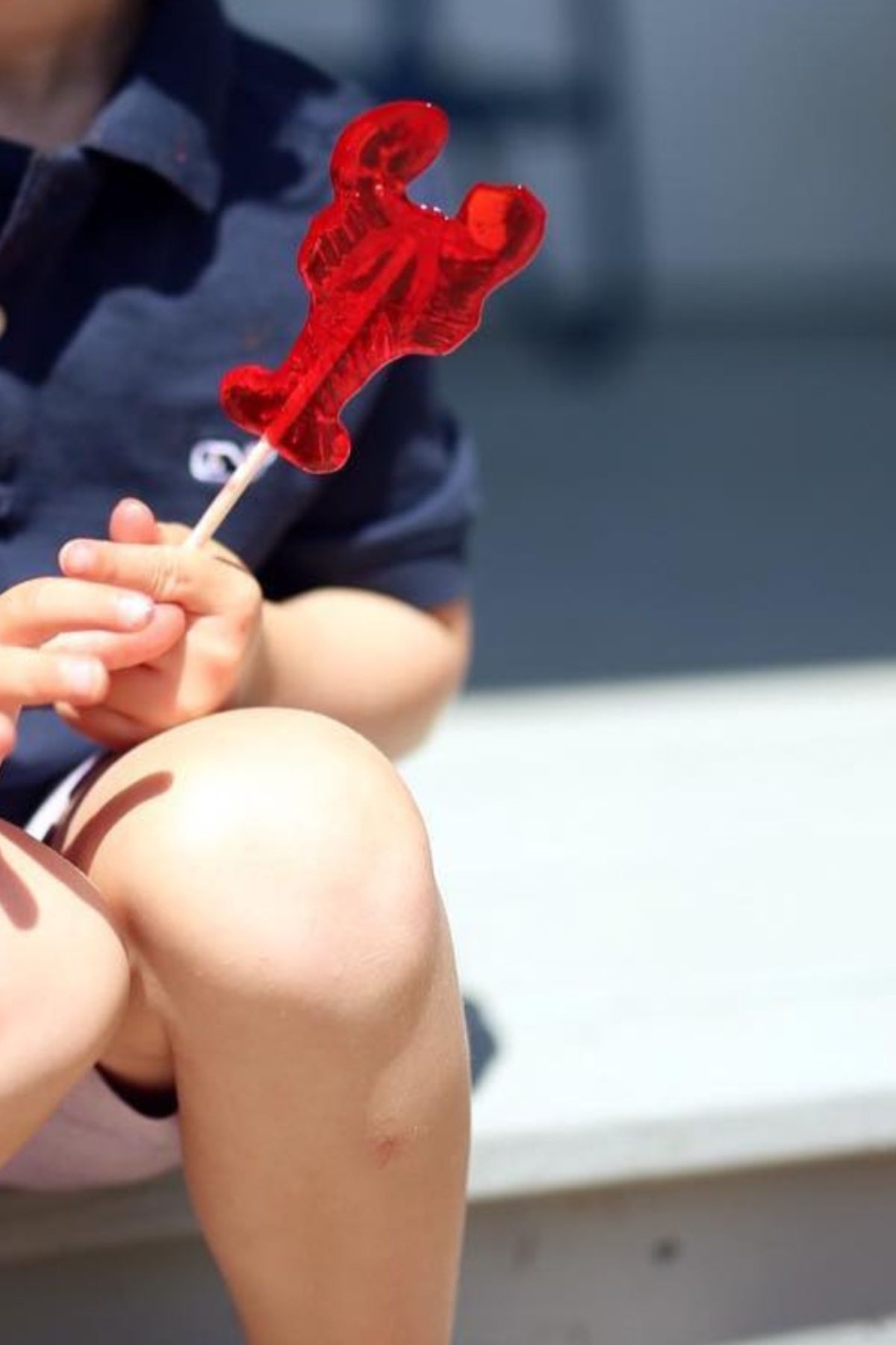 a child holding a red lollipop