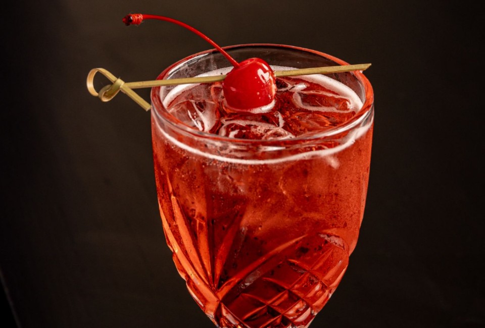 a glass with a drink and a cherry on top