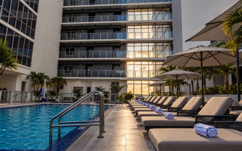a pool with umbrellas and chairs in front of a building