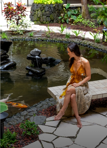 a woman sitting on a bench near a pond