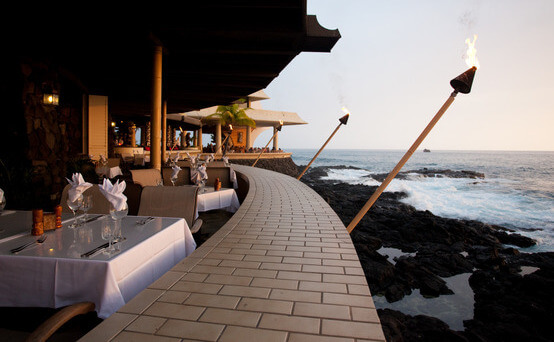 dining tables and tiki torches overlooking the water