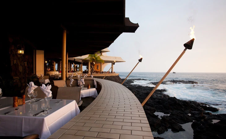 dining tables with tiki torches on the water