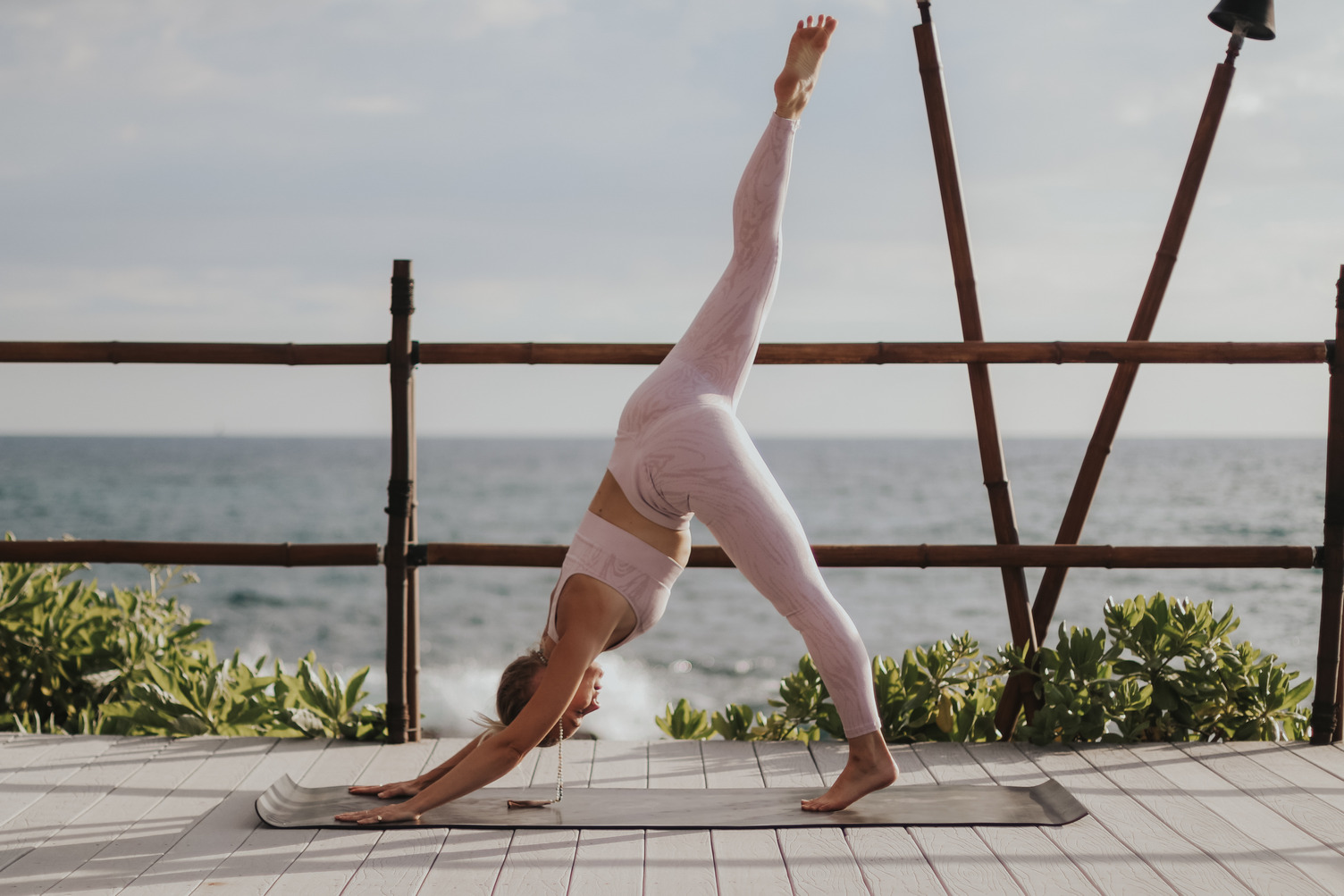 Woman doing a yoga pose with the ocean on the back