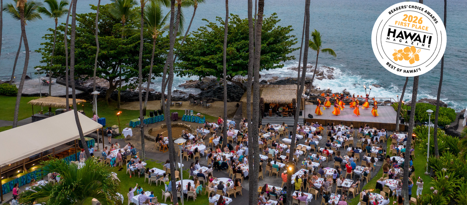 a group of people sitting at tables and a stage at the royal kona resort luau show
