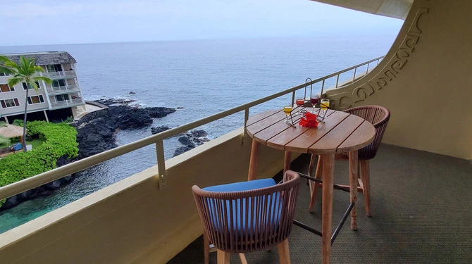 a table and chairs on a balcony overlooking the ocean