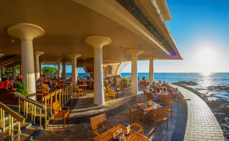 a group of people sitting at tables outside a restaurant