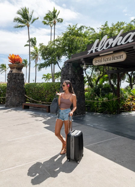 a woman with a suitcase outside of a hotel