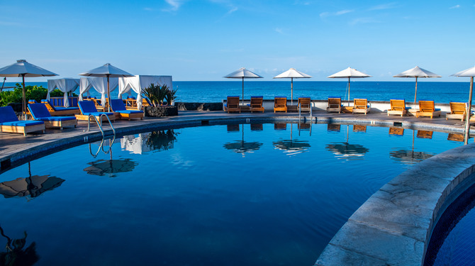 a pool with chairs and umbrellas by the water at Royal Kona Resort