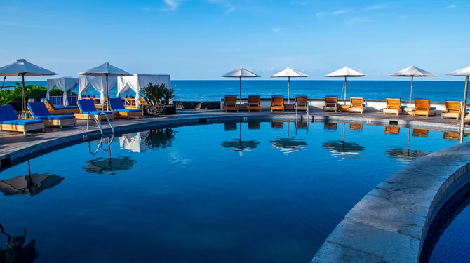 a pool with chairs and umbrellas by the water at Royal Kona Resort