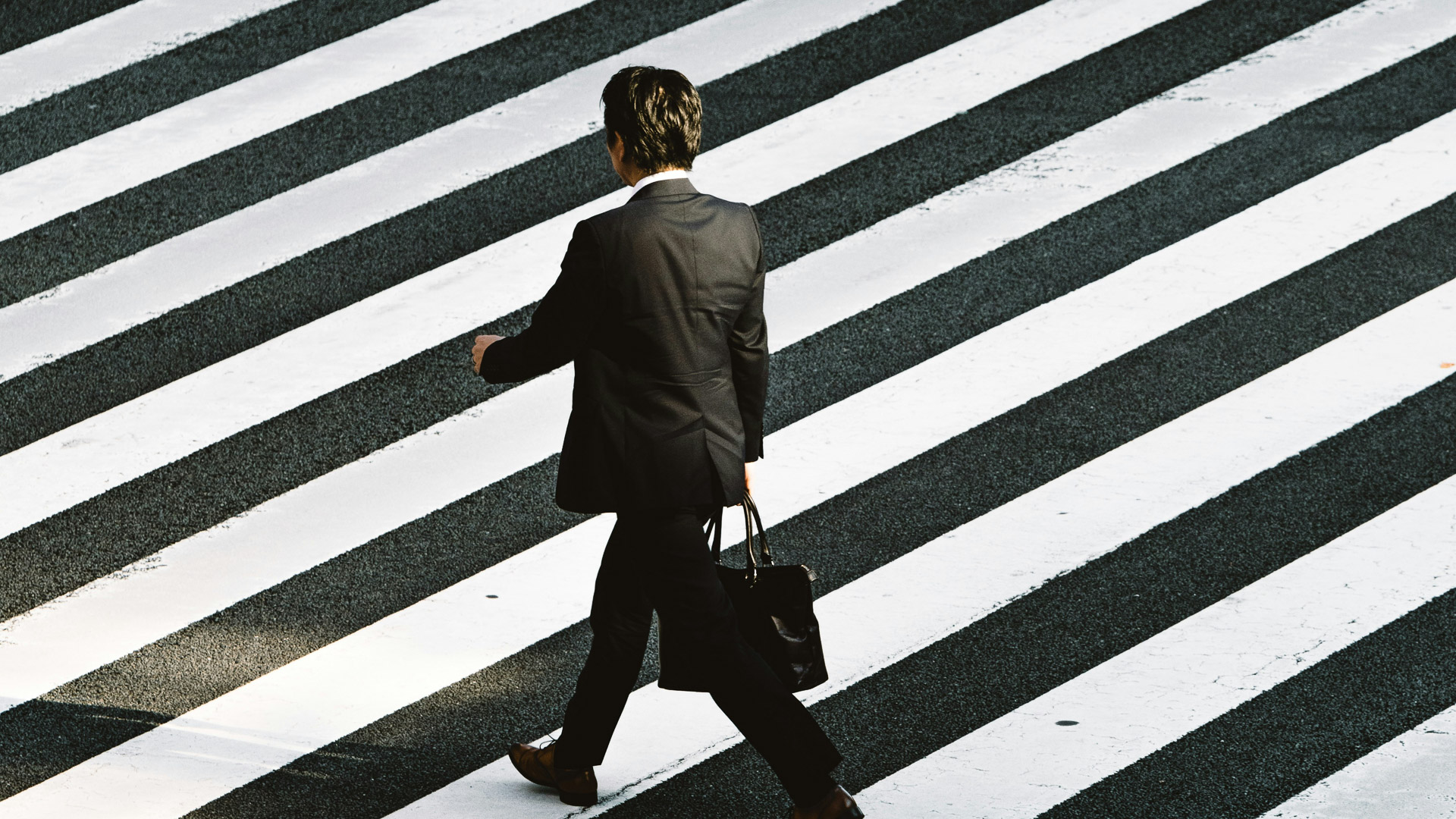 a man in a suit walking across a crosswalk