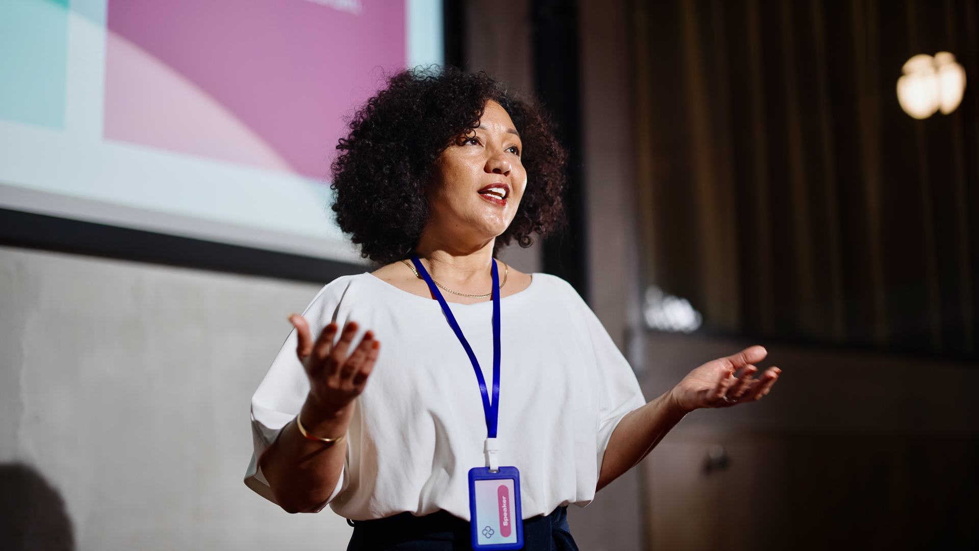 a woman with curly hair wearing a lanyard and a badge
