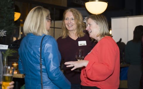 a group of women talking and drinking wine