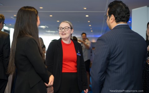 a woman in a red shirt and black suit shaking hands with other people
