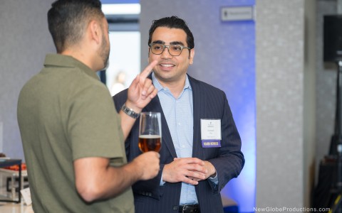 a man holding a glass of beer and talking to another man