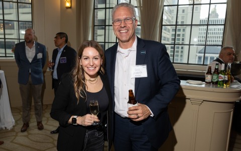 a man and woman holding drinks and standing in a room