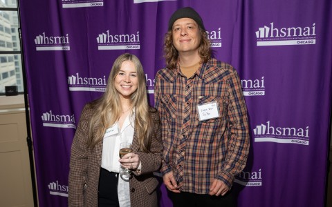 a man and woman standing in front of a purple curtain
