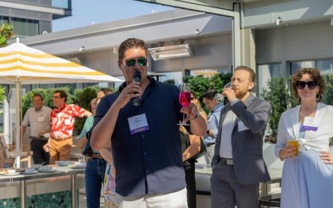 a man holding a microphone and drinking wine