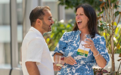 a man and woman laughing while holding wine glasses