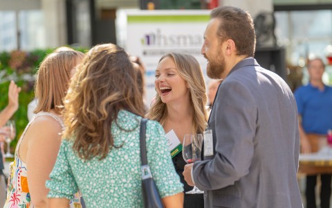 a group of people laughing and drinking wine