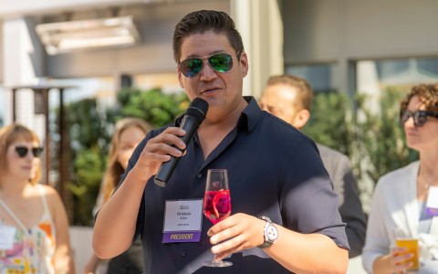 a man holding a microphone and a glass of wine