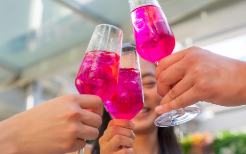 a group of people holding up glasses with pink liquid