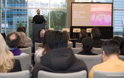 a man standing at a podium with a screen in front of him